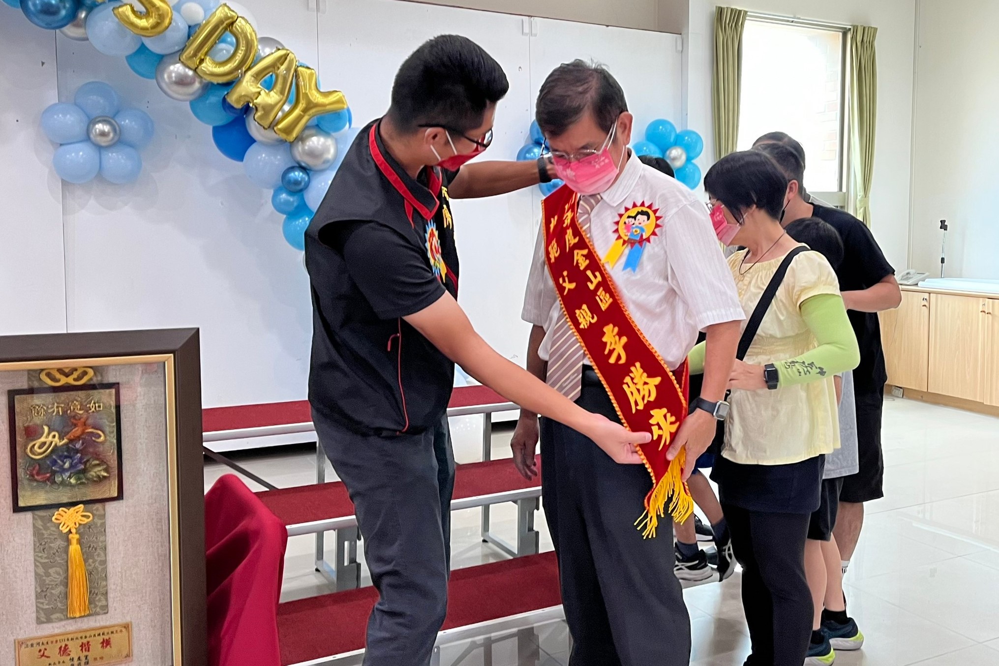 02.區長廖武輝為爸爸們掛背帶獻上祝福